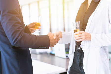 Business people hands shaking hands meeting join together and drinking white wine in office partyの写真素材