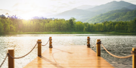 Wood pier dock quiet calm ripple lake with green forest mountain sunny day wide for background.