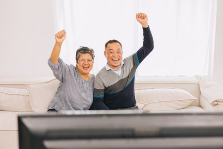 Senior eldely asian family old man and woman enjoy happy watching tv holiday activity together at homeの写真素材