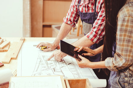 professional architect working with floor plan wooden home furniture and renovate in workshop talking consulting with engineer team.の写真素材