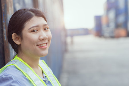 Asian woman happy dock worker control loading containers cargo at shipyard. Marine and carrier staff manager employee. cargo loading operator shipping logistics management.の写真素材