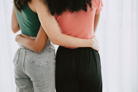 closeup women lover LGBTQ friend living together hands embrace at waist back view mix skin colorの写真素材