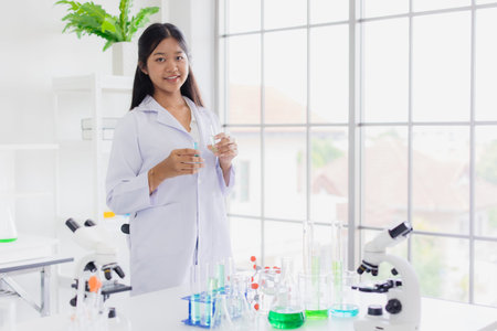 Portrait smart young asian teen scientist girl on white coat role playing in school chemical science...