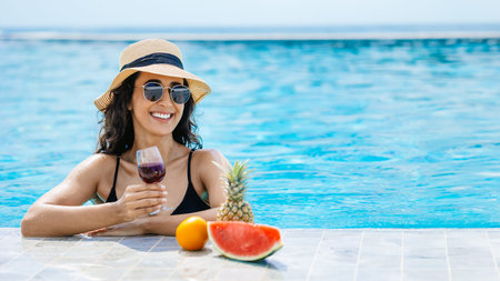 Happy smiling bikini woman enjoy relax at swimming pool with tropical fruits drinks wine summer...