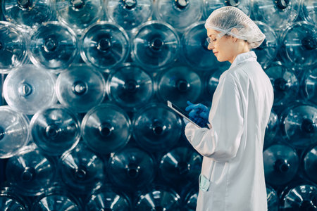 women worker working in drinking water plant factory checking count water bottle gallon in warehouse with hygiene uniform.の写真素材