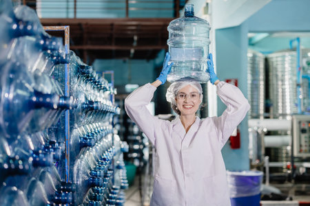 happy women worker working in drinking water plant factory with enjoy work with wate bottle gallon in warehouse with hygiene uniform.の写真素材