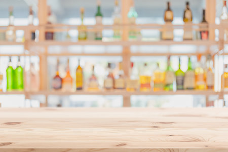 blur cocktail pub restaurant wooden counter bar with alcohol bottles drink mixer full on shelf background for advertising montage.の写真素材