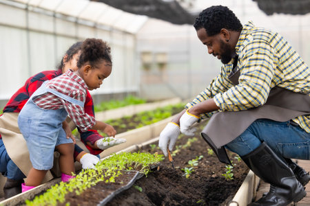 African black child play plant little tree gardening in agriculture farm with family. Children dad mom love nature oganic farming.の写真素材