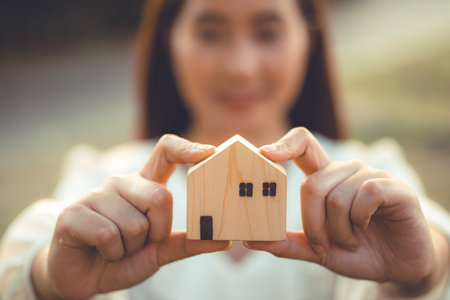 people hand holding miniature wooden house model for banking housing mortgage real estate rent lease home family conceptの写真素材
