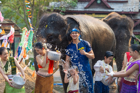 Songkran festival. Northern Thai people in Traditional clothes dressing splashing water together in Songkran day cultural festival with elephant background.の写真素材
