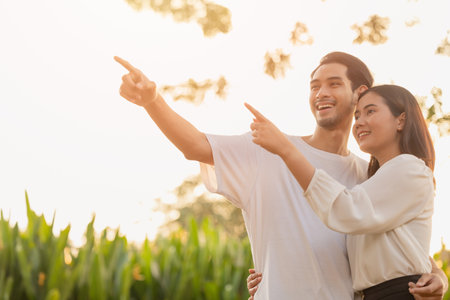 couple teen standing happy smiling together park outdoors sun shining hand pointing high for life planning future insurance business vision conceptの写真素材