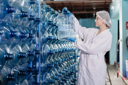 Young caucasian women worker work in drink water factory counting check water bottle gallon stock in hygiene uniform workplaceの写真素材