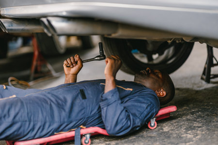 Worker working at under car checking suspension system with sliding bed. Maintenance service in Auto garage.の写真素材
