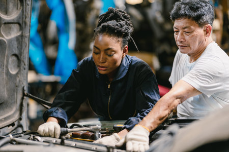 Engineer team working together helping fix service broken car. Women mechanic training in Garage workshop.の写真素材