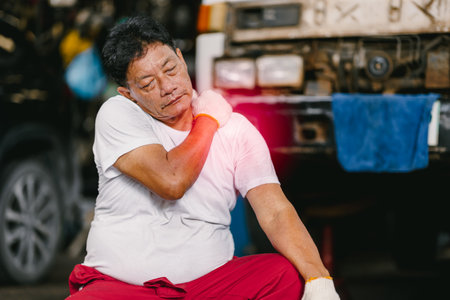 Adult senior Asian worker man muscle join shoulder neck pain syndrome from hard work in heavy industry.の写真素材