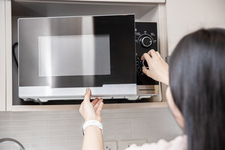 people using the microwave oven, women adjust time to reheat warm food in microwave.の写真素材