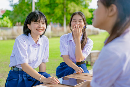 Group of Asian school girls teen friend in school uniform talking leisure together happy laughing at park outdoor green gardenの写真素材