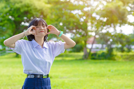 Portrait cute lovely happy Asian student school uniform girl in at green park outdoor pretty handの写真素材