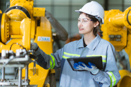 Engineer woman working in advance machine factory. Female worker engineering staff work checking robot arm in assembly plant with tabletの写真素材
