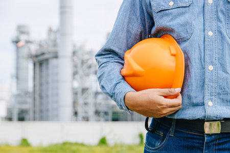 Professional Engineer Male Working Standing Against Oil Gas Refinery Industry Building Closeup Hand Holding Hard Hat.の写真素材