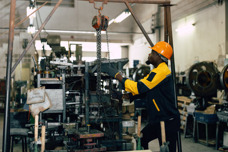 black african worker working in heavy metal industry factory hoist lifting heavy machine partの写真素材