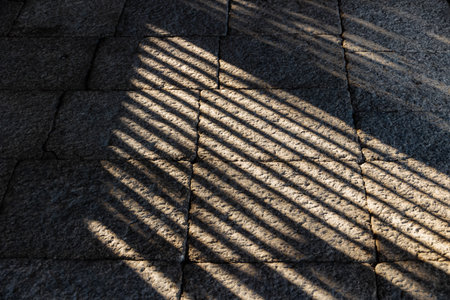 light shade and shadow line through the wooden windows grill holes on rock ground interior line...