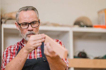 Professional carpenter senior adult man working with wood piece design furniture in workshop in wood factoryの写真素材