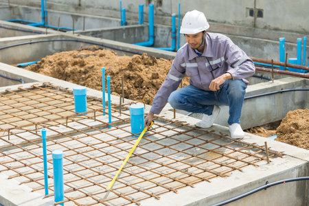 Asian construction engineer, Japanese builder worker male working inspecting footing foundation pipe house building under construction project.の写真素材