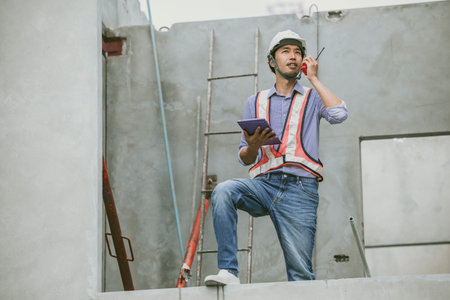 Asian engineer overseeing construction project at construction site, Professional builder working