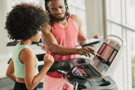 Sport African Afro black girl, Preteen athlete kid training sport exercise activity with trainer man on treadmill in gym school sport clubの写真素材
