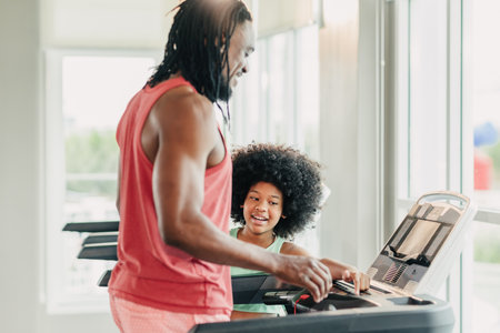 African black healthy dad with playful afro girl child enjoy activity together at sport club holiday, Children father family at fitness gymの写真素材