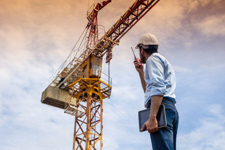 Hispanic Indian professional construction engineer working control operate Crane hoist in construction siteの写真素材
