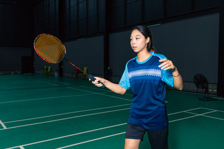 Young woman teen girl enjoy playing badminton handle racket, indoor shuttlecock sport game tournamentの写真素材