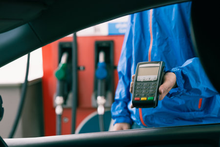 Closeup gas station staff worker with credit card swiping machine for fuel bill payment, Petroleum businessの写真素材