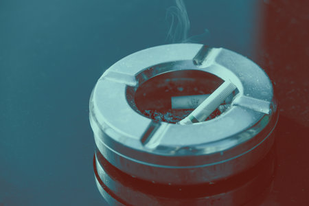 Closeup finished Cigarette butts in ashtray on black empty copy space table top with color effectの写真素材