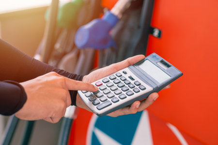 Closeup gas station staff worker hand calculator calculate price car fuel cost low or high price bill, Petroleum businessの写真素材