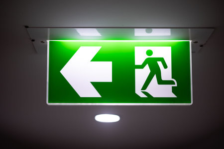 Exit way out arrow direction, Escape guidance sign green color light emergency exit sign in a dark...