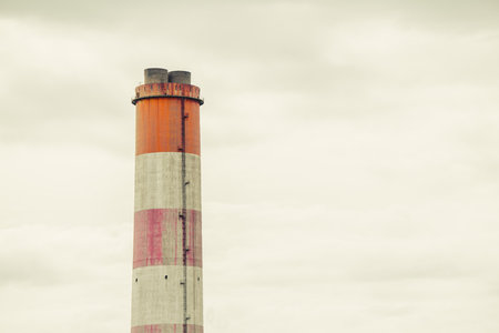 large white red stripe industry chimney, hot gas pipe releases against cloudy sky backgroundの写真素材