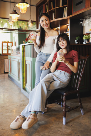 portrait of two beauty Asian women teen sitting together indoor friend happy smilingの写真素材