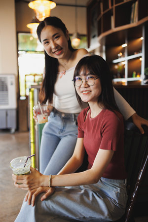 portrait of two beauty Asian women teen sitting together indoor friend happy smilingの写真素材