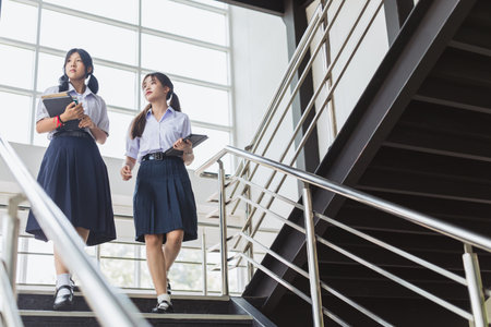 Smart students women teen in uniform standing together at modern school campus indoor. Thai high school student female.の写真素材