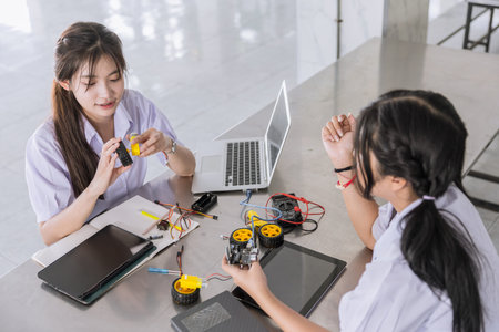 Students teen in uniform learning STEM with iot electricity circuit board component at school campus
