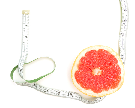 Fresh grapefruit and tape measure and for fitness on white background, concept of slimming, healthy lifestyles and nutritionの写真素材