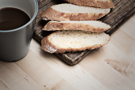 Sliced baguette bread on wooden plate with coffeeの写真素材