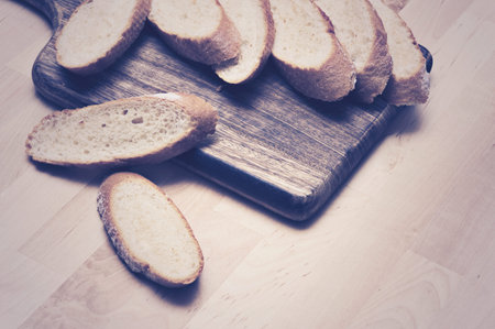 Sliced baguette bread on wooden plate