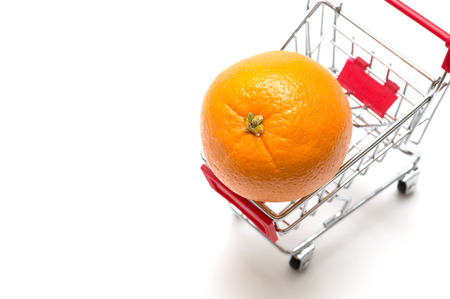 Orange and shopping cart on white background : economy conceptの写真素材