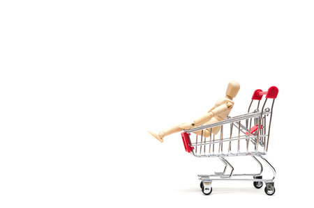 Wooden doll and shopping cart on white background : economy conceptの写真素材