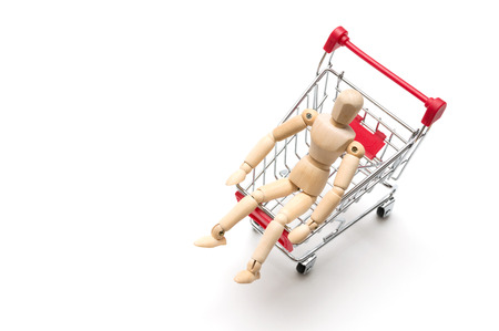 Wooden doll and shopping cart on white background : economy conceptの写真素材