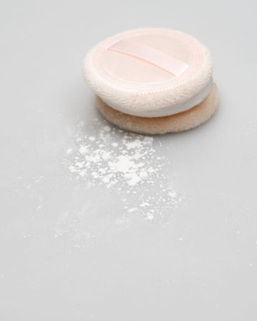 Makeup sponge and powder on white background. Shallow dof.