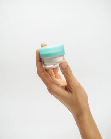 female hands hold a jar of cream on a white background